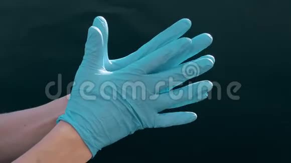 白种人的手戴着蓝色的医用手套黑色背景为医生准备手术医疗程序视频的预览图