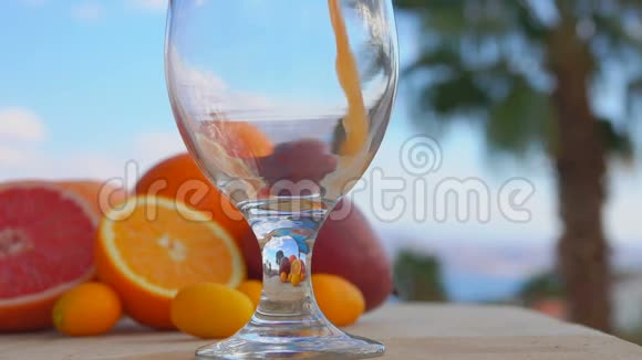 在棕榈树的背景下多种果汁倒入酒杯中视频的预览图