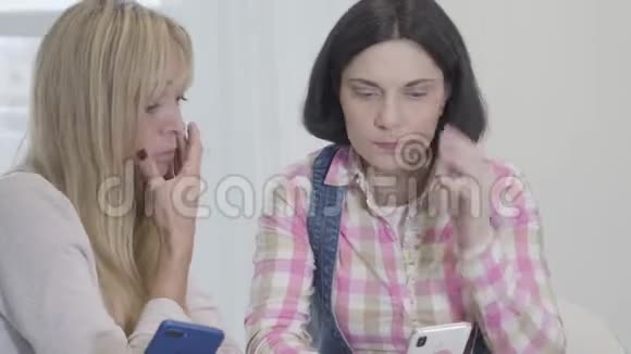 震惊白种人女性朋友坐在智能手机上的肖像面部表情紊乱问题担心视频的预览图