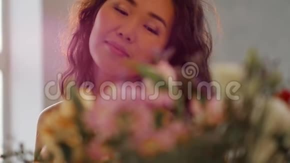 一位美丽的亚洲年轻女子的肖像她穿着一件精致的粉红色连衣裙手里拿着春天的花妇女视频的预览图