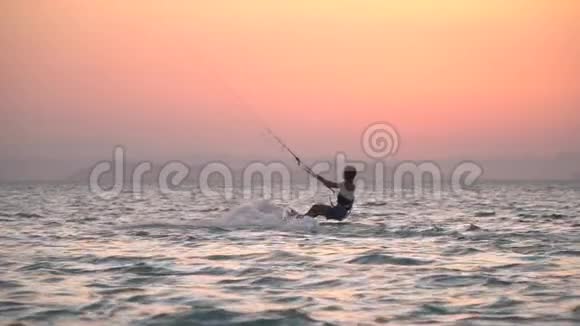 女风筝冲浪者是背卷倒影着大海中的夕阳视频的预览图