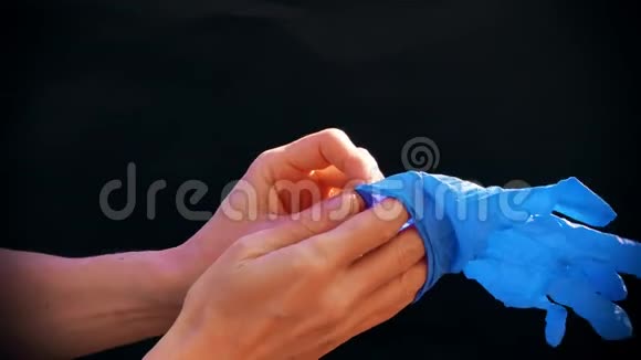 白种人的手戴着蓝色的医用手套黑色背景为医生准备手术医疗程序视频的预览图