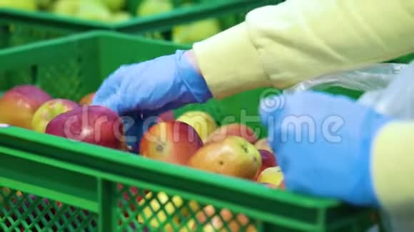 手拿蓝手套在杂货店摘苹果视频的预览图