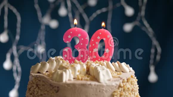 生日蛋糕蓝色背景上有30个数字的粉红色燃烧蜡烛蜡烛吹灭了慢速运动和特写镜头视频的预览图