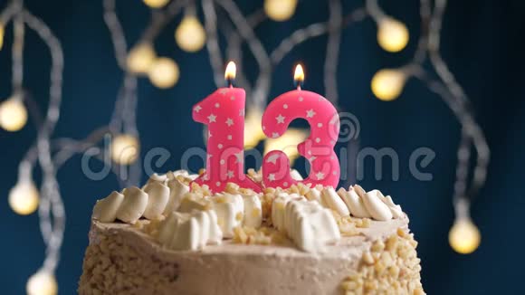 生日蛋糕蓝色背景上有13个数字的粉红色燃烧蜡烛蜡烛吹灭了慢速运动和特写镜头视频的预览图
