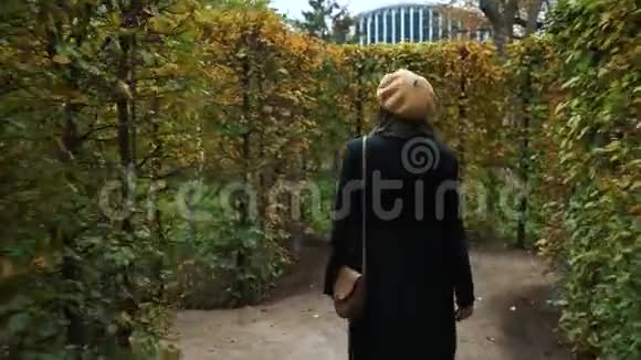 秋天穿着优雅服装在花园迷宫中游荡的快乐女孩视频的预览图