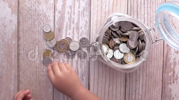 儿童手储硬币在罐子里的俯视图视频的预览图