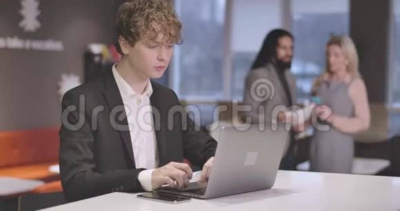 白种人年轻人的肖像卷发在笔记本电脑键盘上打字自信成功的CEO的肖像视频的预览图