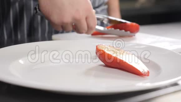 完美的用餐理念男主厨的特写镜头用钳子夹在盘子里用葡萄酒煮熟的美味的红梨视频的预览图