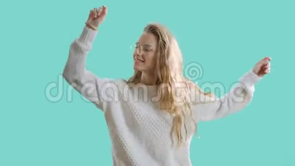 快乐的年轻女人在蓝屏背景下跳舞和微笑积极的青少年女孩戴着彩色眼镜视频的预览图