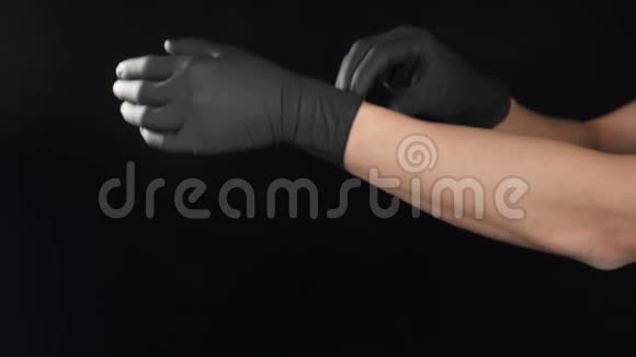 男医生在手术前戴上黑色防护手套在黑色背景上射击索夫运动视频移动男视频的预览图