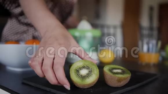 女孩从桌子上拿猕猴桃来榨果汁模糊的视频的预览图