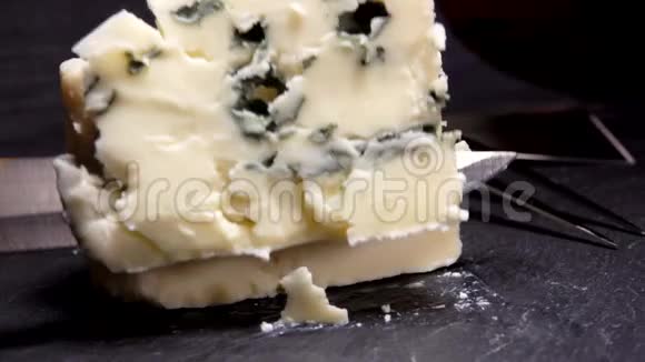 刀把黑石板上的一块蓝金奶酪切开并举起视频的预览图