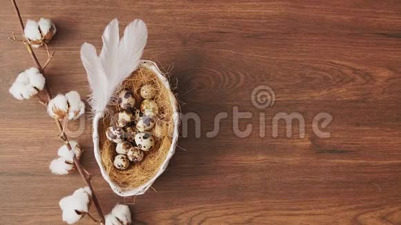 羽毛落在木桌上的巢里的复活节彩蛋上复活节节日装饰品复活节概念背景视频的预览图