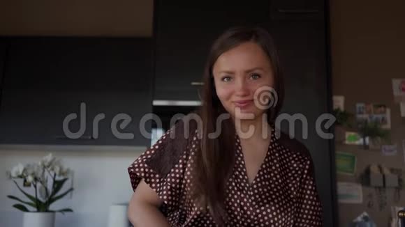 一幅美丽的微笑女人用榨汁机在厨房准备新鲜果汁的画像视频的预览图