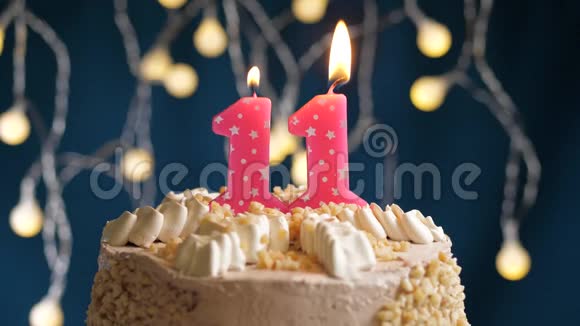 生日蛋糕蓝色背景上有11个数字的粉红色燃烧蜡烛蜡烛吹灭了慢速运动和特写镜头视频的预览图
