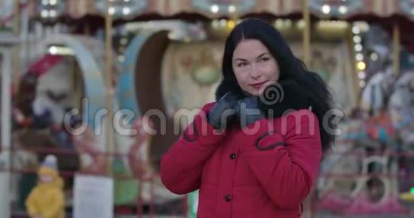 迷人的成年白种人女人穿着红色外套站在城市市场上环顾四周中年妇女肖像视频的预览图