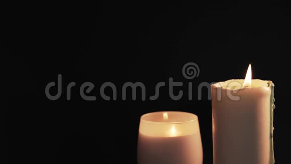 两支白色燃烧的蜡烛被隔离在黑色的背景上希望和信仰的概念视频的预览图