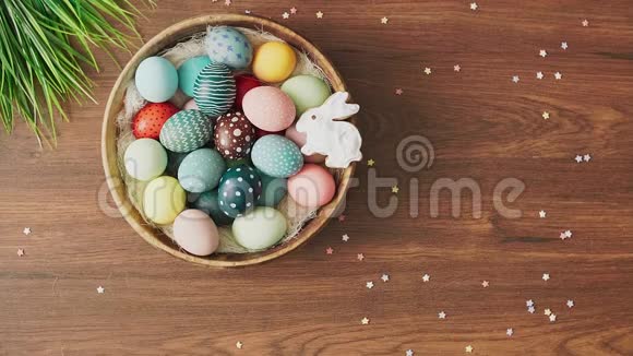 双手在装饰好的木桌上放下满是彩色复活节彩蛋和郁金香的巢复活节节日装饰品复活节视频的预览图