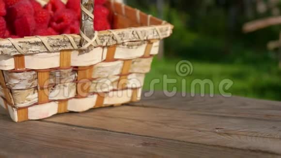 满是成熟的红色甜树莓的桦木篮子正落在一张木桌上视频的预览图