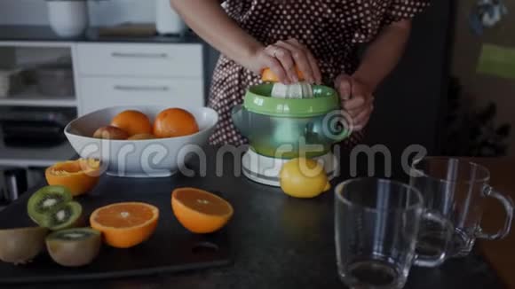 女人用电动榨汁机准备新鲜橙汁关门视频的预览图