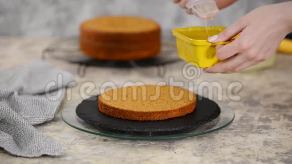 无法辨认的女性糖果手用硅制料刷将海绵蛋糕与甜焦糖糖浆浸泡在视频的预览图