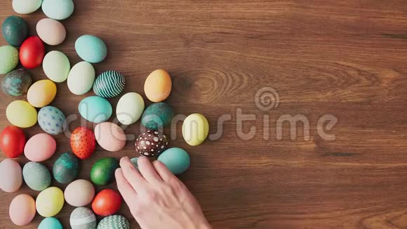 手拿木桌上五颜六色的复活节彩蛋复活节节日装饰品复活节概念背景视频的预览图