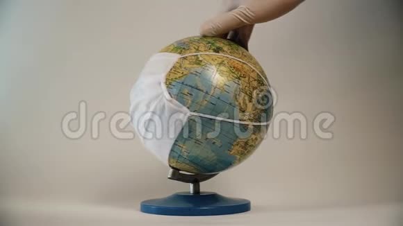 戴上手套用白色背景上隔离的医用面罩旋转地球地球仪全球大流行covid19冠状病毒视频的预览图