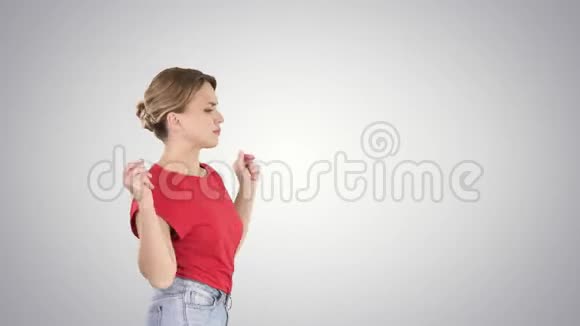 年轻女子穿着红色t恤牛仔裤在梯度背景下跳舞和散步视频的预览图