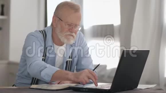 一位戴着眼镜留着胡子的老人在电脑上工作的肖像并通过银行账户在网上支付视频的预览图