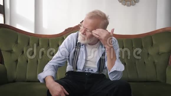 偏头痛是一位留着胡须戴着视力眼镜的老男性目前正经历着令人难以忍受的头痛视频的预览图