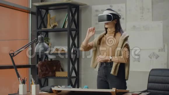 年轻的女工程师戴着虚拟现实头盔用手做动作模仿图形的工作视频的预览图