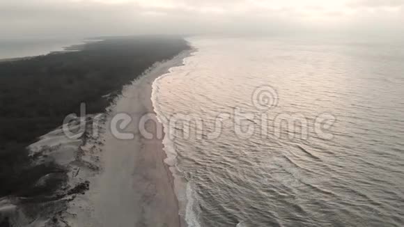 日落后蓝色小时的波罗的海海岸鸟瞰图暮光的海岸线带着滚滚的波浪空旷的海滩视频的预览图