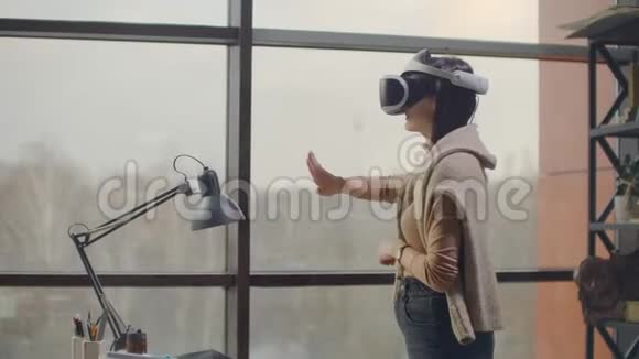 肖像一位戴着虚拟现实头盔的女建筑师在一间靠近一扇大窗户的现代化办公室里用手视频的预览图