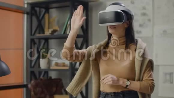 在虚拟现实头盔办公室里年轻的女设计师用手做动作模仿图形作品视频的预览图