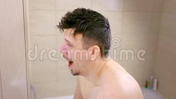 睡意朦胧的年轻人在浴室镜子前伸展早上打哈欠视频的预览图