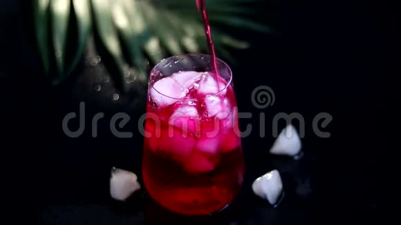 覆盆子巴宝莉饮料在透明玻璃与冰饮料倒入玻璃杯中添加棕榈枝和覆盆子视频的预览图