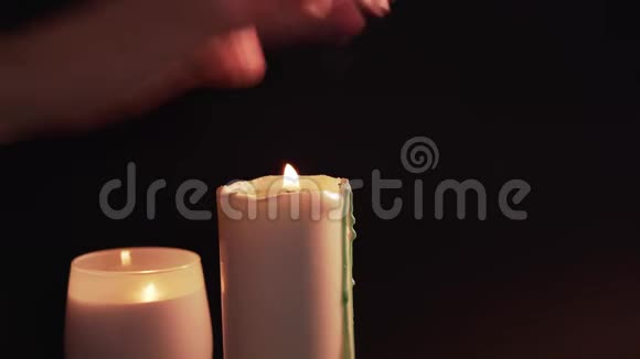 一个女人试图在黑色背景上熄灭蜡烛两支燃烧的蜡烛隔离浪漫的夜晚结束视频的预览图