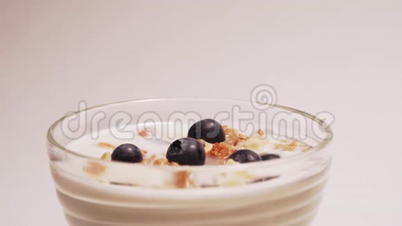 蓝莓倒在纯素酸奶透明玻璃健康早餐在牛奶中加入浆果状的维生素视频的预览图
