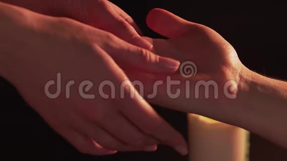 女人手在男人手掌上预测孤立在燃烧的蜡烛旁边的黑色背景上的概念视频的预览图