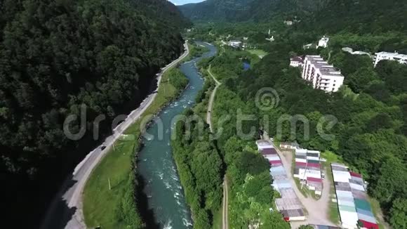 公路附近的湍急的山溪和茂密的森林绕山与城市聚居慢动作空中照片视频的预览图