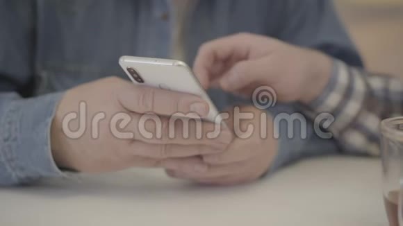 高级男性高加索手握智能手机的极端特写镜头年轻男性在屏幕上滑动无法辨认的成年人视频的预览图