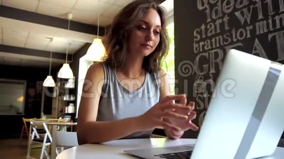 慢动作女学生在咖啡馆用笔记本电脑工作视频的预览图