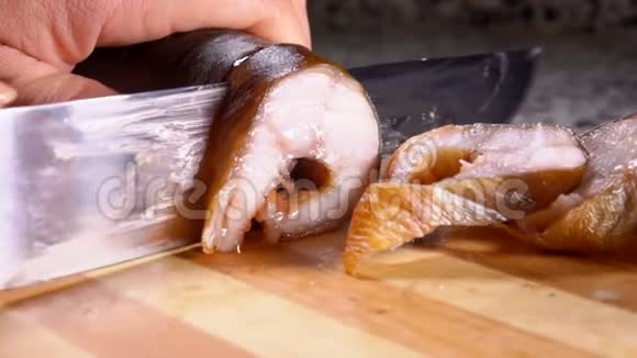 手把美味的熏鳗鱼切成切片用刀子放在木板上视频的预览图