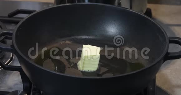 一种热的煎锅一个女人把一块黄油放在上面它融化并流动视频的预览图