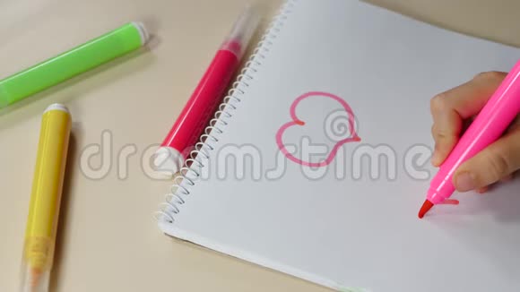 孩子用粉红色的记号笔把心画在纸上一个孩子手画特写孩子们创造力视频的预览图