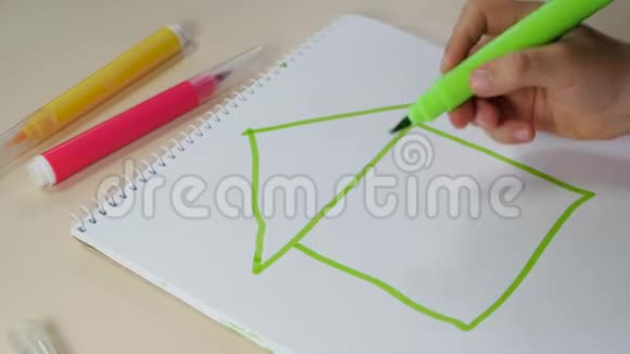 小手的特写一个孩子在桌子上用白纸画房子幸福童年的概念视频的预览图