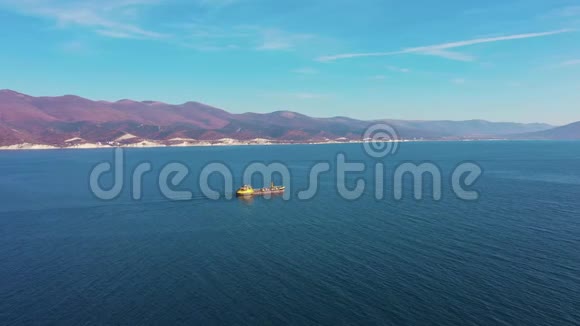 货船在平静的蓝色海面上沿着群山航行视频的预览图