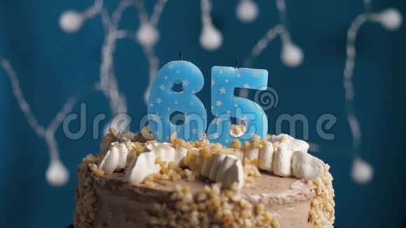 生日蛋糕上面有65个数字蜡烛在蓝色的背景上蜡烛吹灭了慢动作和特写视频的预览图