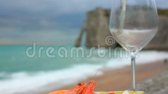 将白葡萄酒倒入背景上有虾和柠檬的玻璃杯中视频的预览图